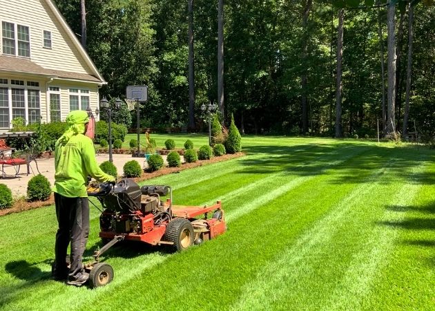 Rauda Landscaping team member mowing a residential lawn